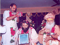 Pujya Bhaishri and Pujya Swami Gurusharananandji Maharaj give blessings and flowers to Pujya Swamiji